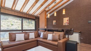 Una sala moderna con un sofá modular, una mesa de centro de vidrio y una chimenea.