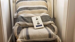 Une chambre confortable avec une fenêtre, une literie à rayures et une table de chevet sur laquelle repose un livre.