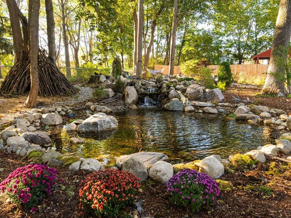 A garden with a pond, rocks, and colorful flowers.