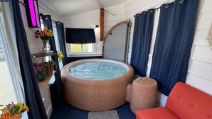 Une pièce chaleureuse avec un jacuzzi, un canapé rouge et une fenêtre avec des rideaux.