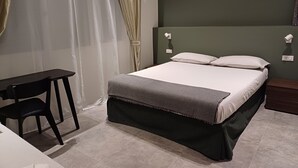 Ein ordentlich eingerichtetes Schlafzimmer mit Bett, Schreibtisch und Stuhl.