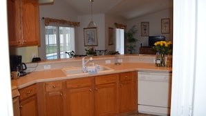 A kitchen with wooden cabinets, a built-in dishwasher, a sink, and a dining area with a table and chairs.