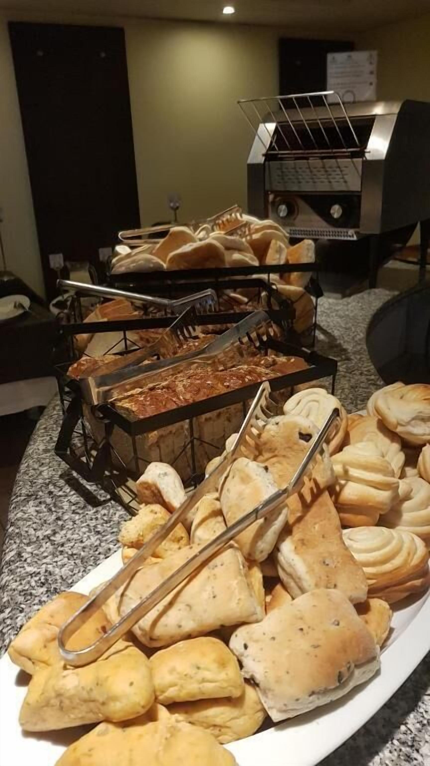 A buffet with various baked goods including bread, rolls, and pastries.