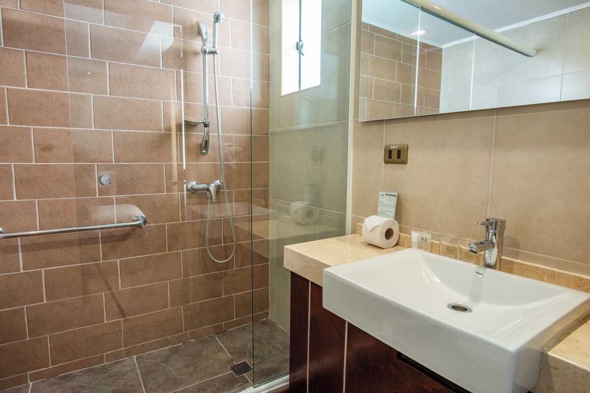 A modern bathroom with a glass shower enclosure, a white sink, and a mirror above it.