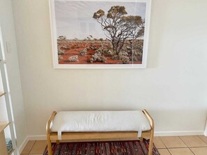 Relax in a serene space with a comfortable bench and a beautiful landscape painting.