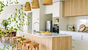A modern kitchen with a central island, wooden cabinets, and hanging wicker light fixtures.