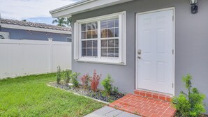 A residential house with a white door, a window with white shutters, and a small garden with various plants. - Hollywood Hideaway: Close to Dtwn & Beaches (Hollywood)