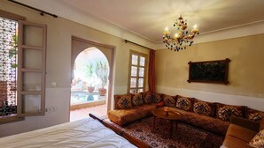 A bedroom with a large bed, a sofa, a small table, and a chandelier. - Riad salix agafay (Saada)