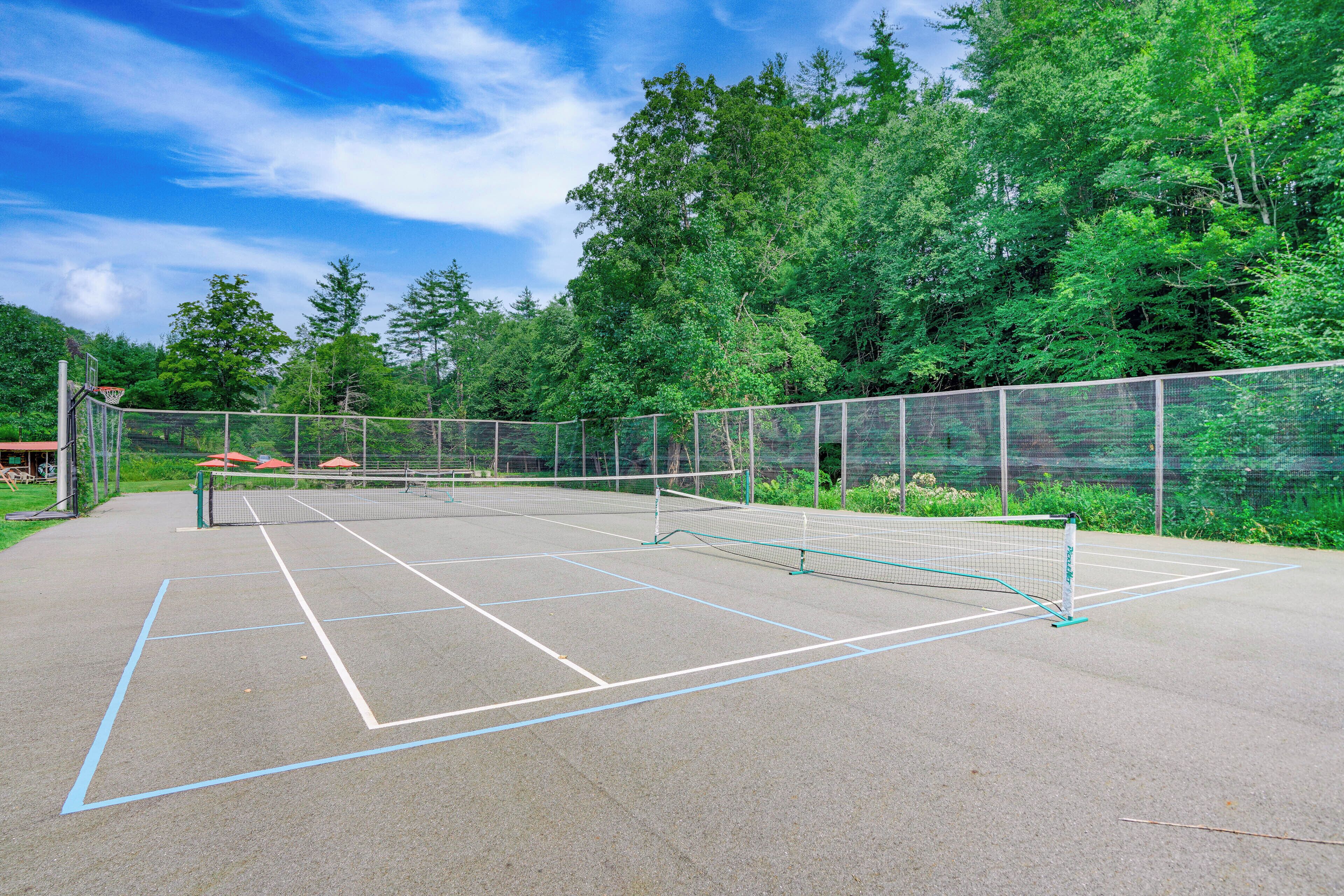 Een tennisbaan buiten, omringd door bomen.