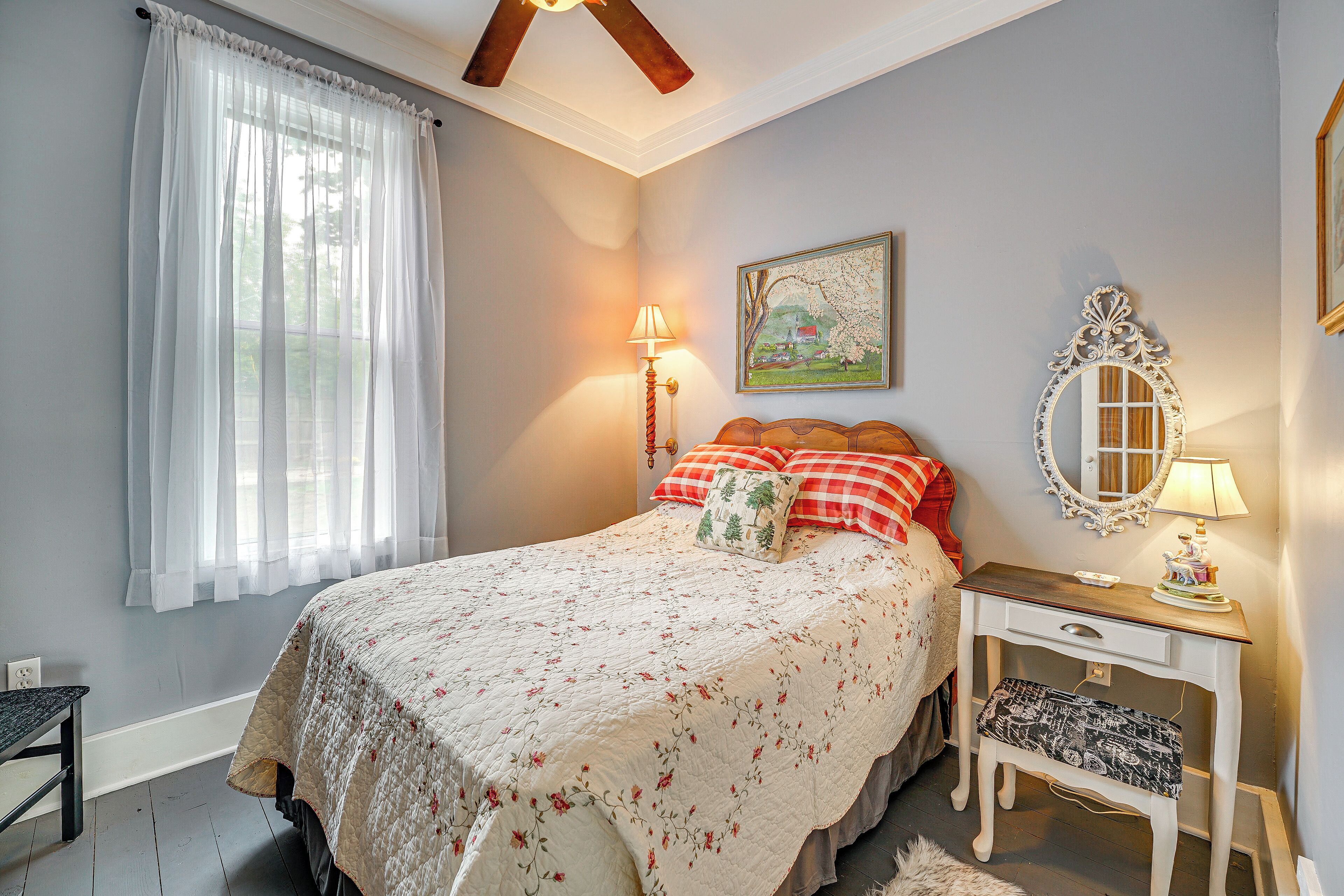 A bedroom with a bed, bedside table, lamp, and a mirror.