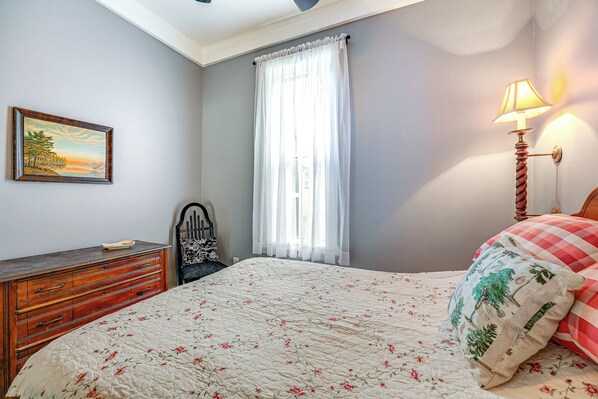Ein Schlafzimmer mit Bett, Kommode, Lampe und einem Gemälde an der Wand.