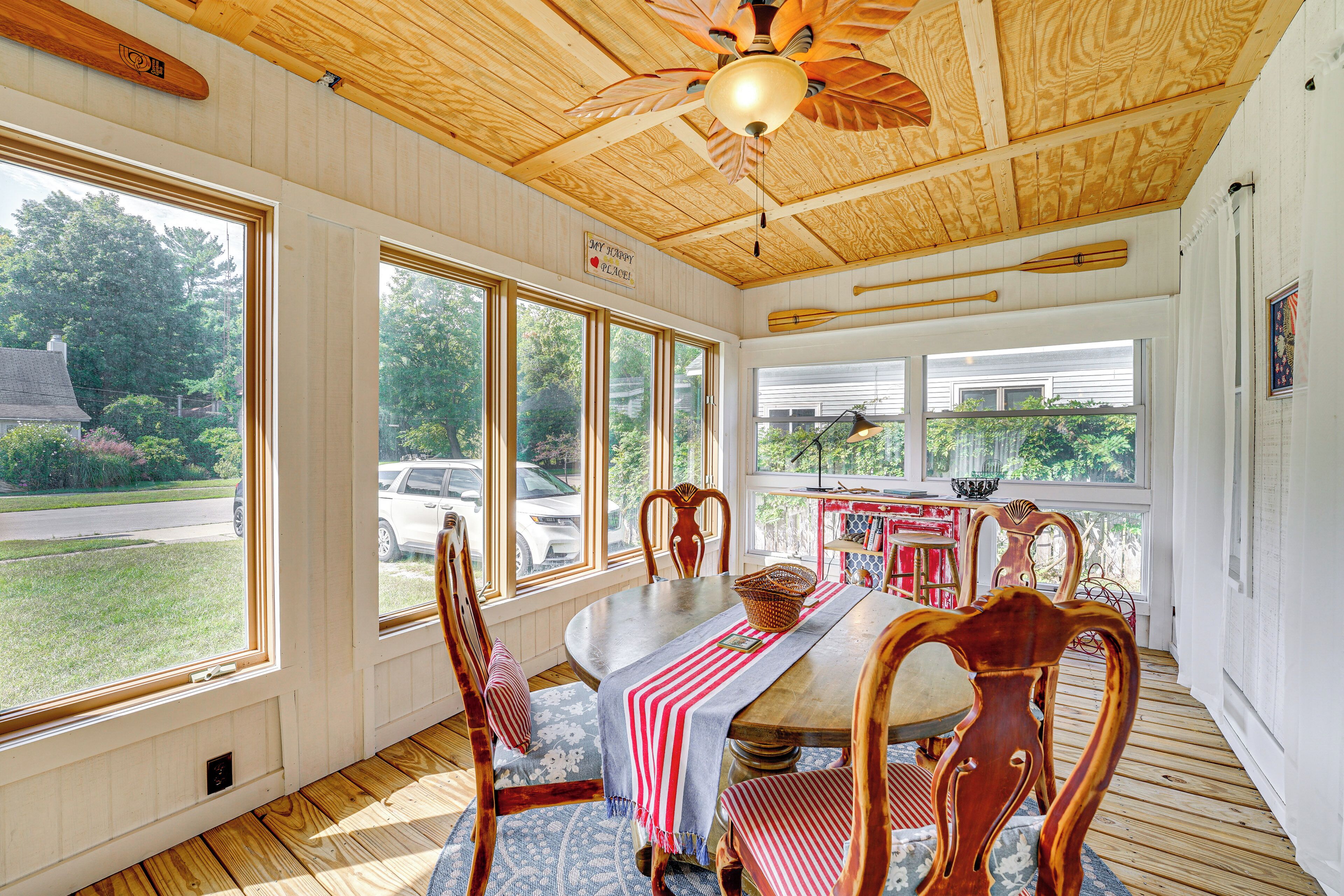 A dining area with a wooden ceiling, large windows, and a view of the outside.