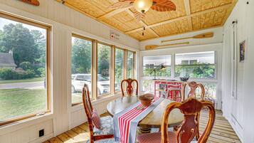 A dining area with a wooden ceiling, large windows, and a view of the outside.