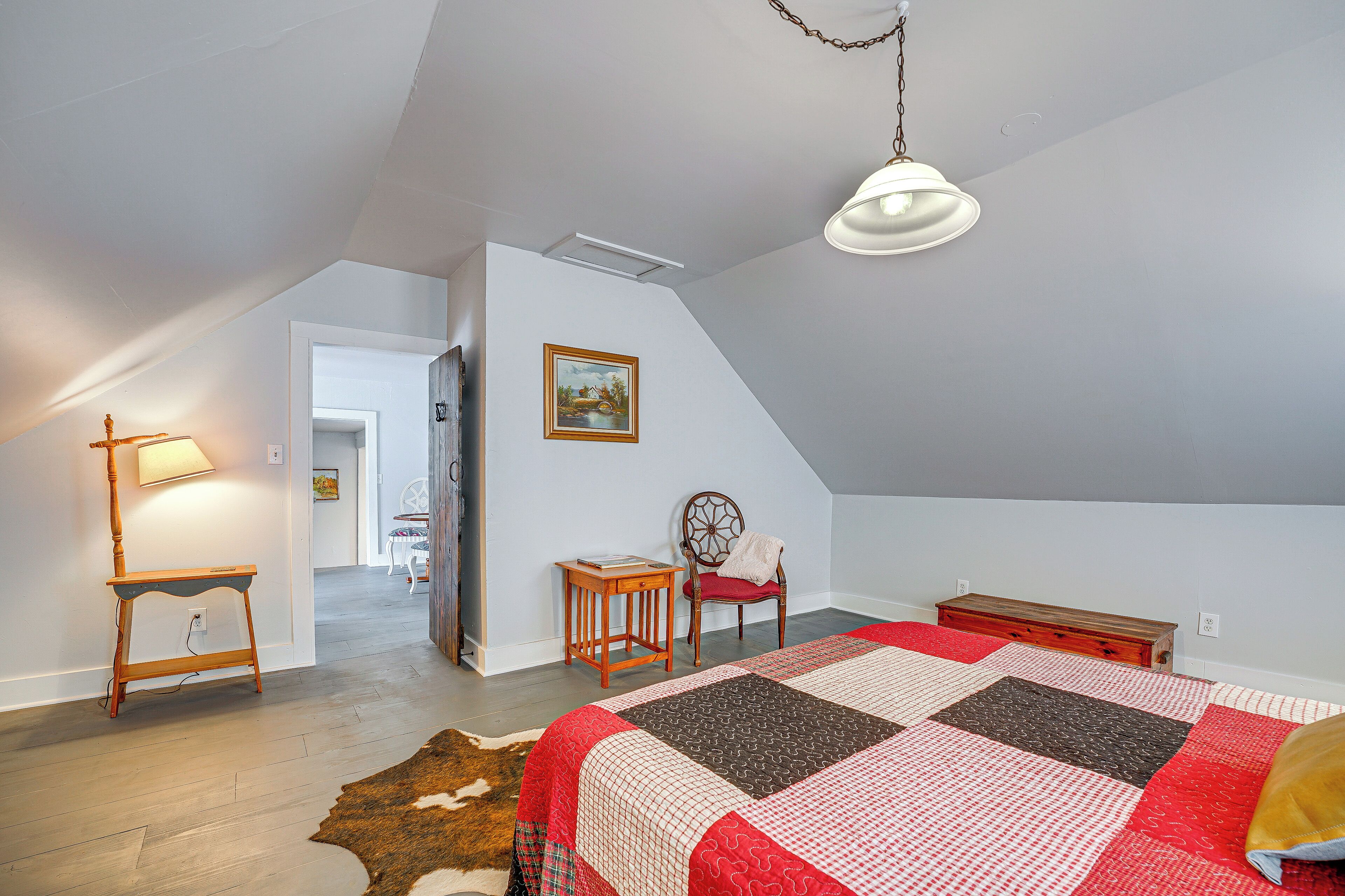 Un dormitorio con una cama grande, un escritorio, una silla y una lámpara colgante.