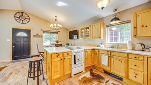 A kitchen with wooden cabinets, a stove, and a large island with stools.