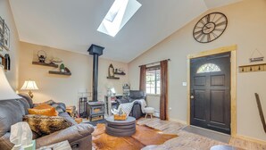 A cozy living room with a leather sofa, a round coffee table, a fireplace, and a wooden door with a glass window.