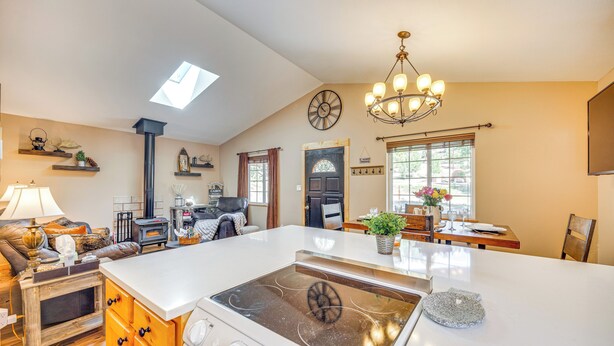 A spacious kitchen with a central island, a built-in stove, and a dining area with a chandelier.