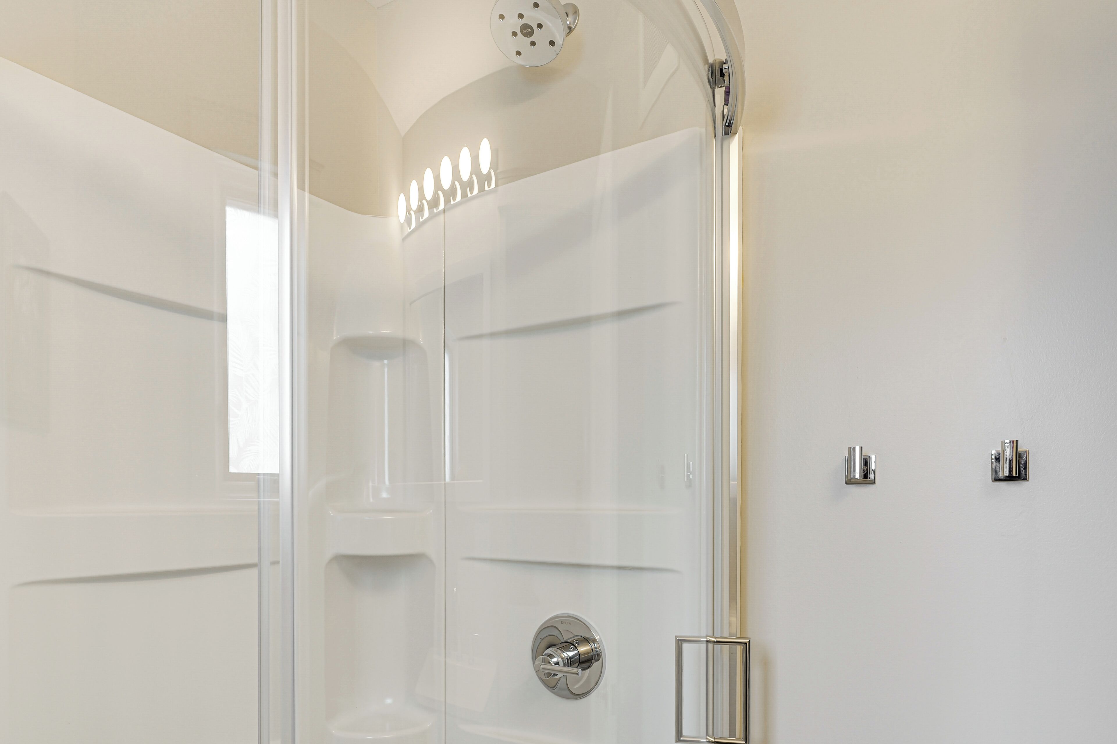 Un box de ducha moderno con puerta de cristal, ducha empotrada y panel de control.