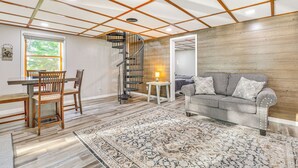 A room with a dining table, chairs, a sofa, a patterned rug, and a spiral staircase. - Okee Bay House on Lake Wisconsin w/ Private Dock! (Lodi)
