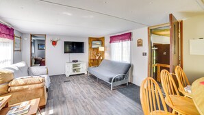 A furnished room with a sofa, a bed, a TV, a wooden cabinet, and a dining table with chairs. - Yale Home in the Heart of Pheasant Hunting Country (Yale)
