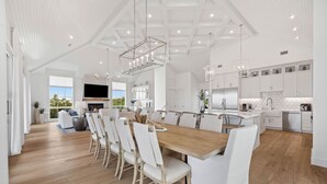 A spacious kitchen with white cabinetry, a wooden dining table, and a large window offering a view of the outdoors.