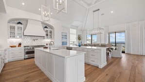 A spacious kitchen with white cabinetry, a large island, and a view to the outside.