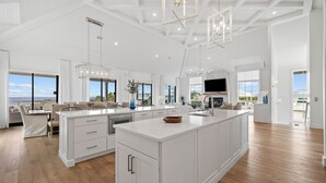A spacious kitchen with a large island, white cabinetry, and a view of the outdoors.