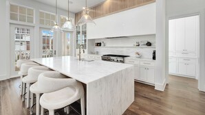 A modern kitchen with a large island, bar stools, and pendant lighting.