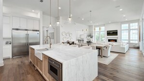 A modern kitchen with a large island, stainless steel appliances, and pendant lighting.