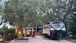 Un campeggio con camper e tavolo da picnic all'ombra degli alberi.