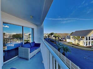 A balcony with wicker furniture and a view of a residential street. - Maravilla #1306 | Pet Friendly, Near Beach + Resort Amenities (Miramar Beach)