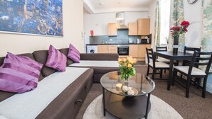 Una sala moderna con un sofá, una mesa de centro de vidrio y un comedor con sillas y una mesa.