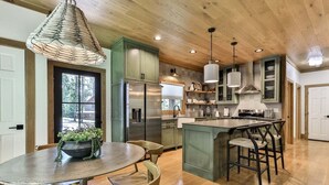 A modern kitchen with wooden cabinets, a central island, and pendant lighting. - Francis Oaks by Mountain Oasis | Luxury Cabin in Coosawattee River Resort (Ellijay)