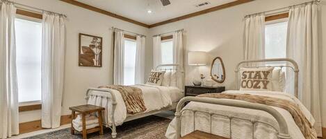 A bedroom with two beds, a ceiling fan, a rug, and a bedside table.