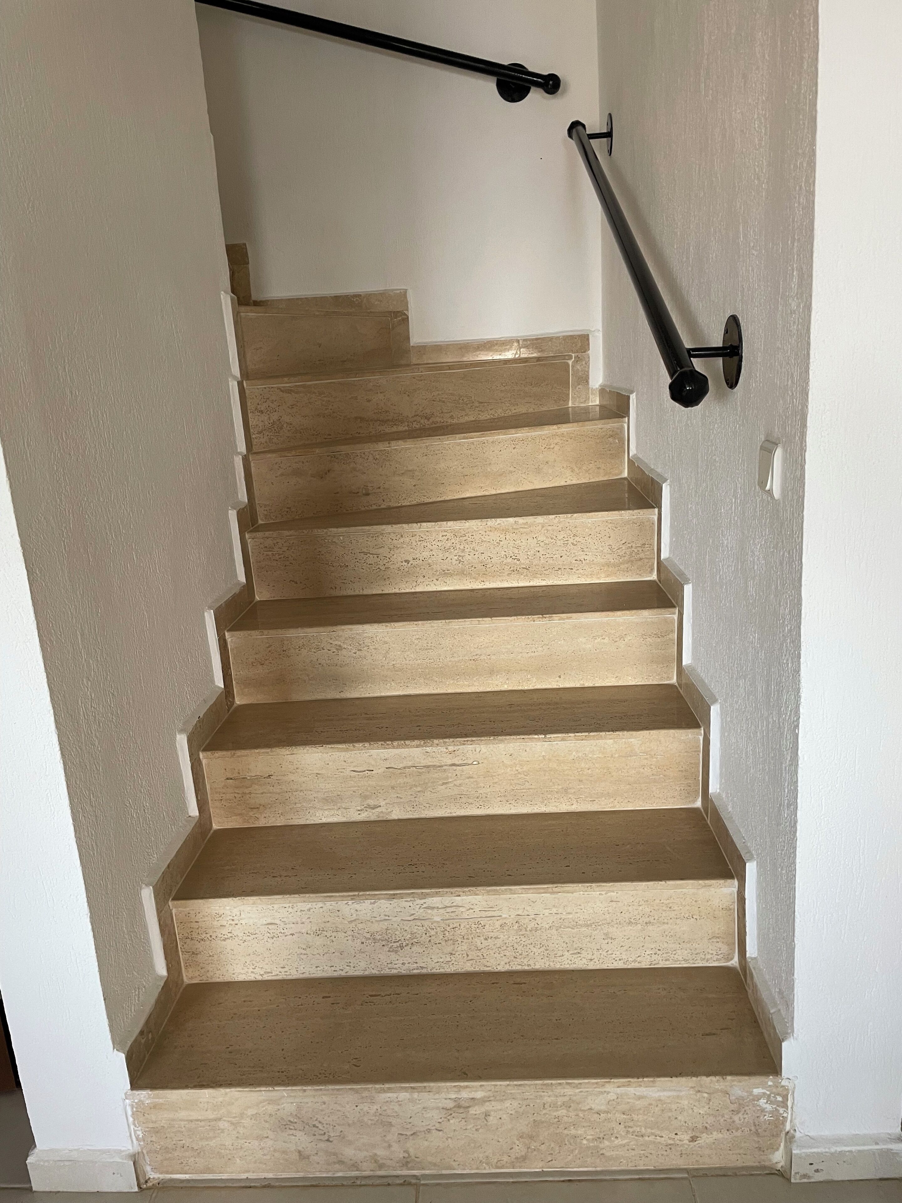 A staircase with beige steps and black handrails.