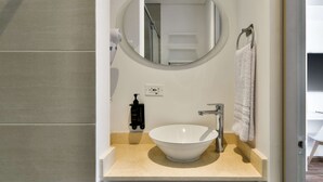 A bathroom with a white sink, a round mirror, a towel rack, and a soap dispenser. - w Stylish Loft w Brilliant Deco in Chapinero (Bogotá)