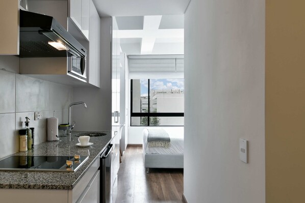 A modern kitchen with a built-in oven, a sink, and a window overlooking a cityscape.