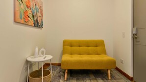 A room with a mustard-colored sofa, a small white table with a vase and a pen, and a colorful abstract painting on the wall. - w Stylish Loft w Brilliant Deco in Chapinero (Bogotá)