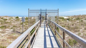A wooden boardwalk leading to a beach area with a metal fence and a 'Keep Off' sign. - Seaside Haven Stylish Condo 3 Pools New Rental (St. Augustine)