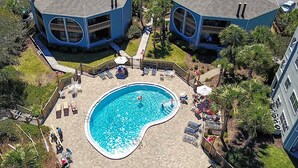 An aerial view of a residential area with two blue houses, a swimming pool, and surrounding greenery. - Seaside Haven Stylish Condo 3 Pools New Rental (St. Augustine)