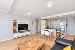 A modern living room with a flat-screen TV, a coffee table, and a sofa.
