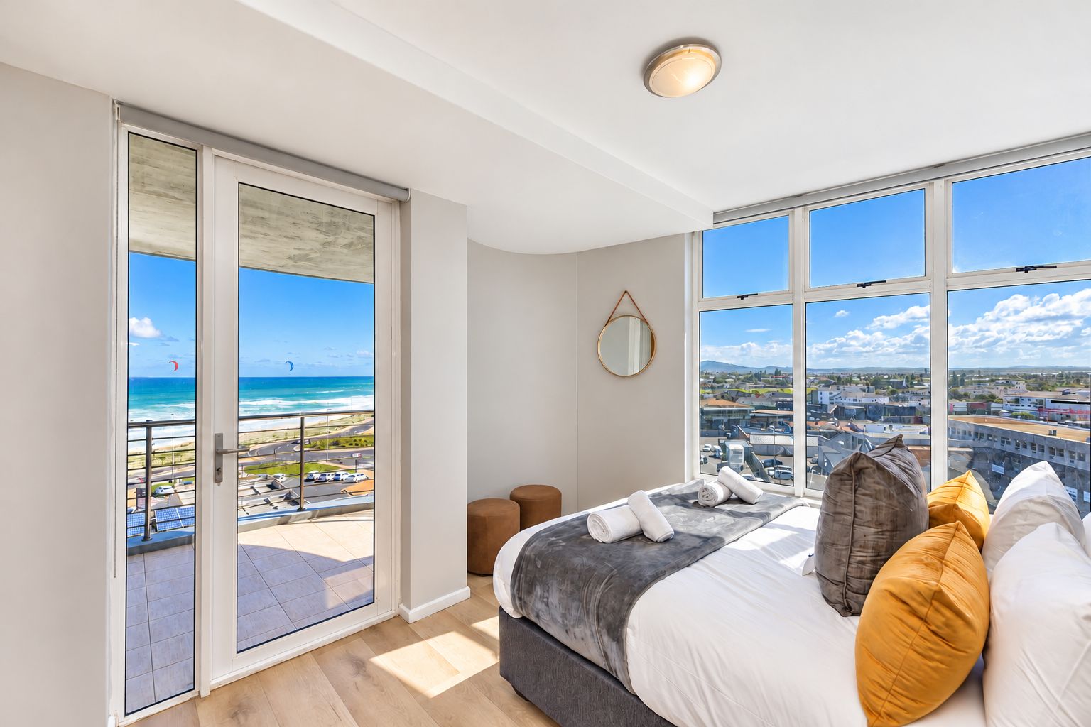 A bedroom with a large bed, a view of the ocean, and a balcony with a glass door.