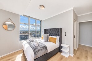 A modern bedroom with a large bed, a view of the city, and a minimalist design.
