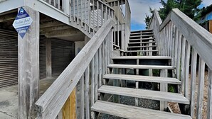 A wooden staircase leading to a building with a closed garage door. - The Sassy Sea Turtle | Spacious + Pet-Friendly Retreat, Just Steps From The Beac (Topsail Beach)
