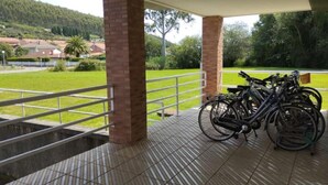 Ein überdachter Außenbereich mit gefliestem Boden und Ziegelpfeilern. Fahrräder stehen an der Wand geparkt.