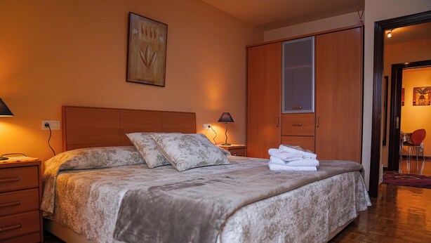 Ein Schlafzimmer mit einem großen Bett, einem Holzschrank und einem Nachttisch mit Lampe.