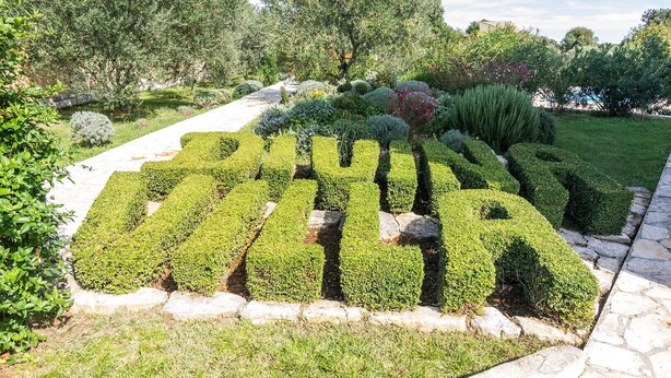 A well-maintained garden with neatly trimmed hedges and a stone pathway. - Villa Divina in Sisan (Sisan)