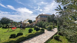 A well-maintained garden with a stone pathway, neatly trimmed hedges, and a swing set. - Villa Divina in Sisan (Sisan)