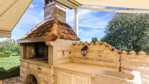 An outdoor stone barbecue with a chimney, a stone bench, and a lamp. - Villa Divina in Sisan (Sisan)