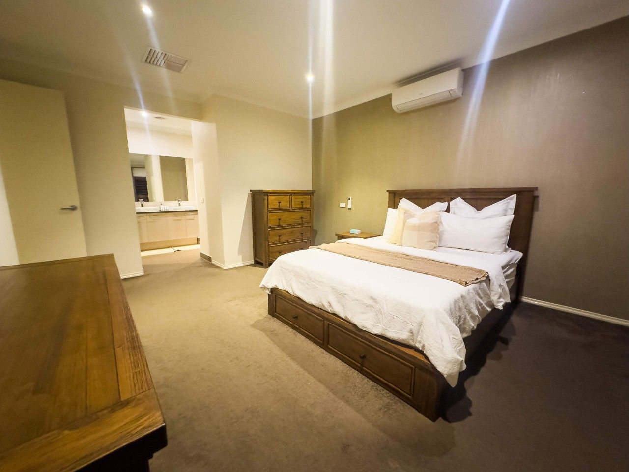 A bedroom with a bed, wooden dresser, and a small table.